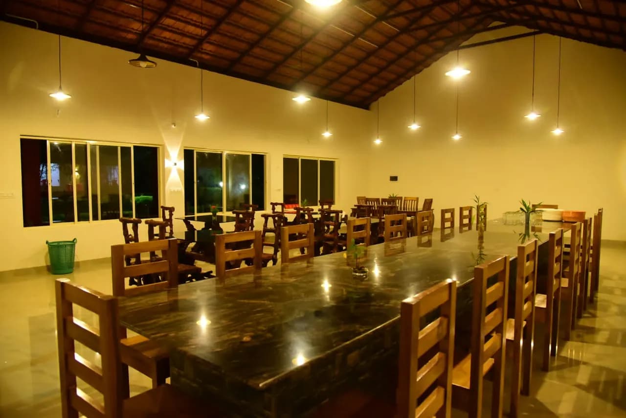 The dining hall lit warm in the evening, long wooden tables laid out beneath the tiled roof