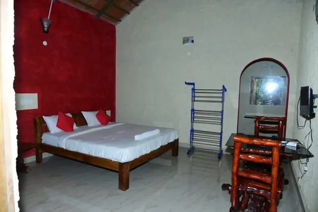 Double bed with red cushions against a deep red accent wall