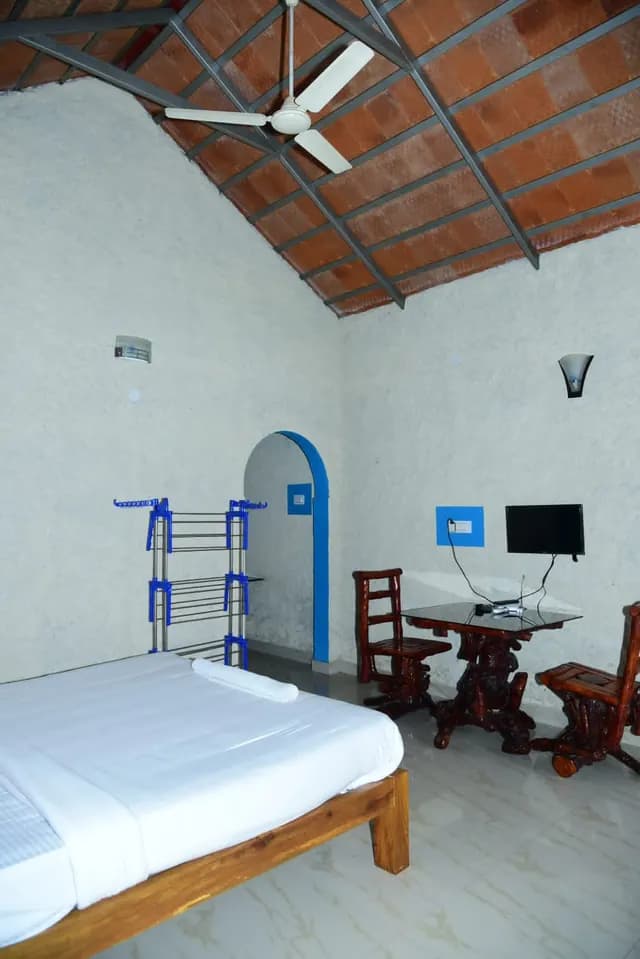 Twin-bedded room under a pitched tiled ceiling with a table and chairs